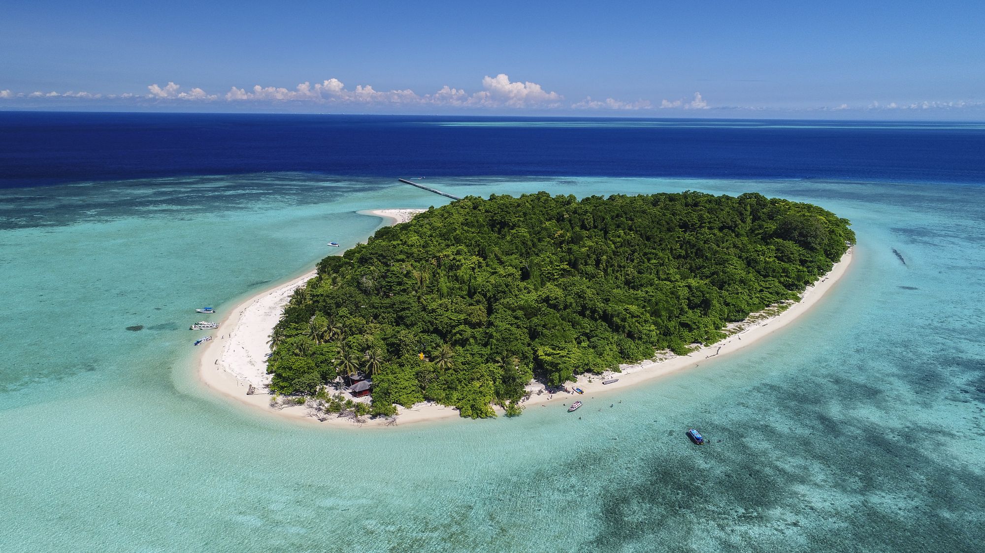Sangalaki Island in the Derawan Islands, ringed by white sand and shallow reef, seen from the air