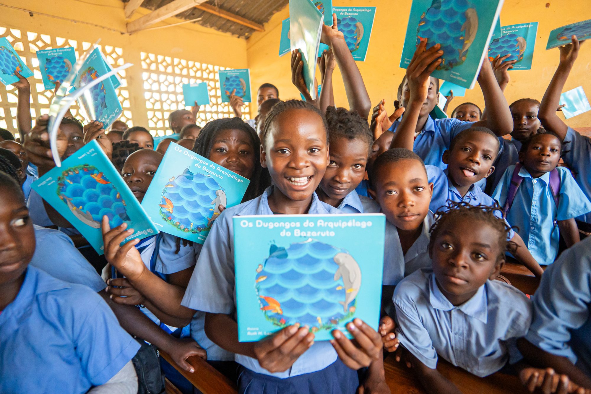 Students at a school near Inhassoro hold up copies of the Portuguese-language dugong book after a lesson