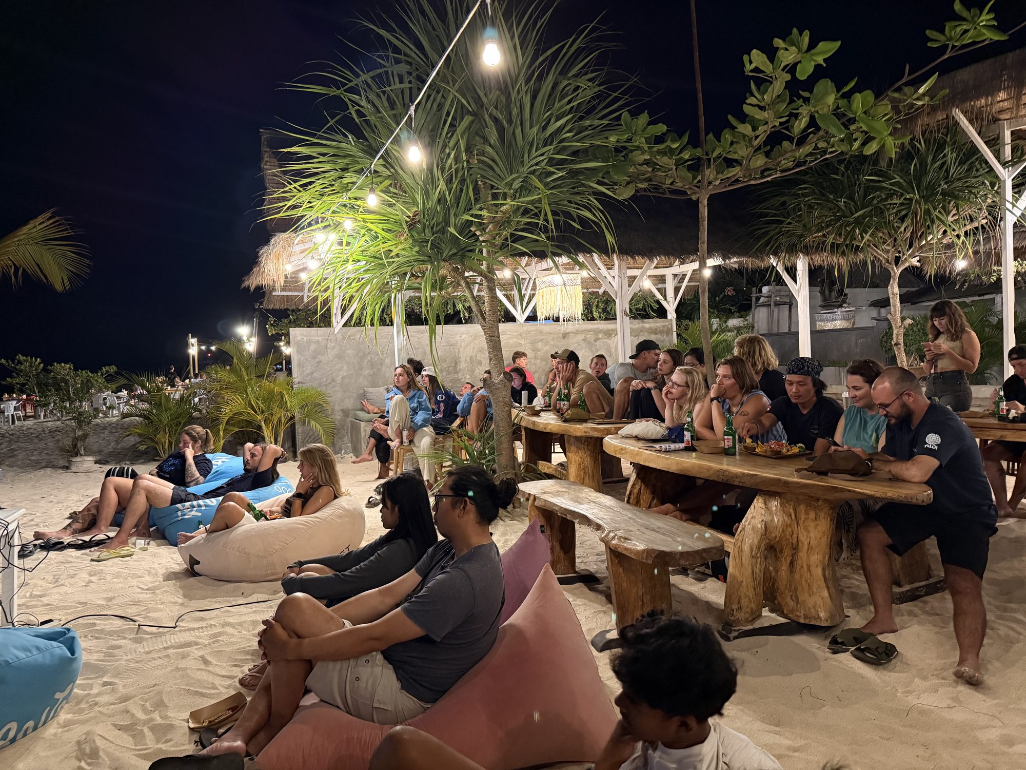 An audience gathers on a beach at Nusa Lembongan for an evening Mola Talk