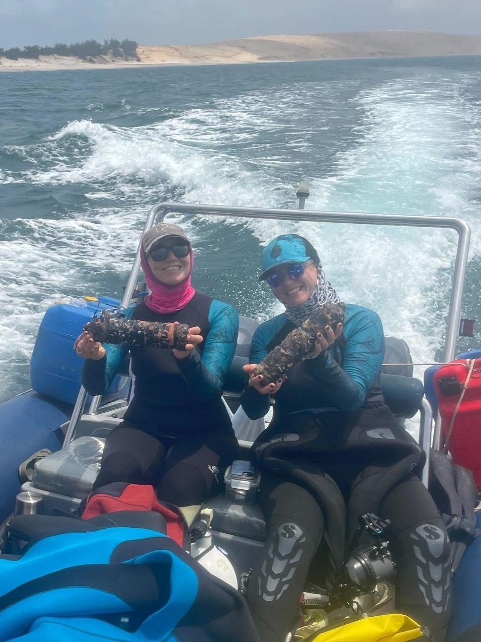 Two MMF researchers on a boat hold receivers covered in marine growth after recovering them from the reef