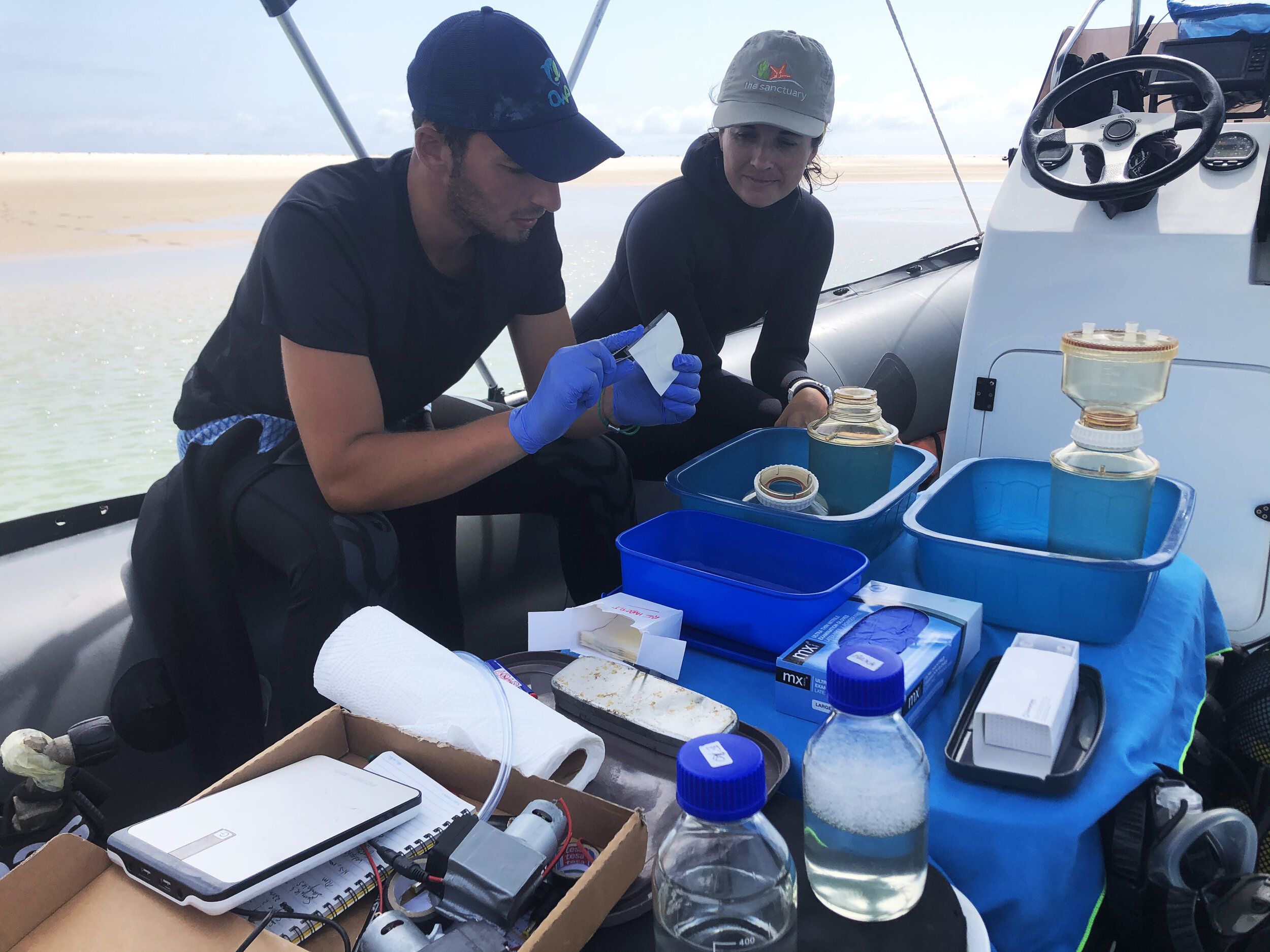Two researchers process water samples for environmental DNA on a boat in the Vilanculos Coastal Wildlife Sanctuary